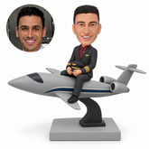 custom bobblehead figure male pilot seated astride a sleek jet airplane on a curved display stand