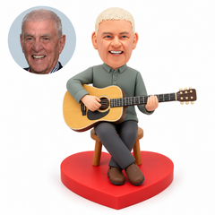 custom bobblehead figure man playing an acoustic guitar seated on a round stool with crossed ankles