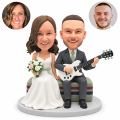 custom bobblehead figures wedding couple seated together with the groom playing an electric guitar and the bride holding a bouquet