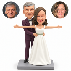 custom bobblehead figures wedding couple with the bride stretching both arms sideways and the groom holding her waist from behind