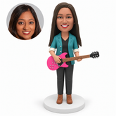 custom bobblehead figure woman holding a horizontal electric guitar at her waist with her left palm supporting the neck