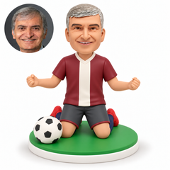 custom bobblehead figure male soccer player kneeling on both knees with both fists raised at his sides and a football beside his right knee