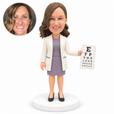 custom bobblehead figure female eye doctor holding an eye chart in her left hand with her right arm lowered