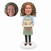 Custom female pastry chef bobblehead holding a decorated cake on a platter