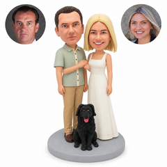 Custom clay bobblehead couple clasping hands at chest height beside a fixed seated black dog, with matching real portrait photos.