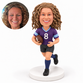 Female rugby player with her left leg forward, right arm holding one ball and open left hand at waist