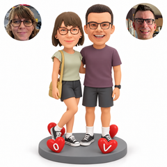Custom clay couple, woman left with crossed leg and shoulder bag, man right, four fixed heart ornaments on an oval base