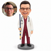 Male doctor bobblehead holding a navy-and-yellow rod in his right hand with his left arm lowered