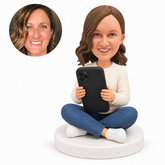 custom bobblehead figure woman sitting cross legged with a large phone