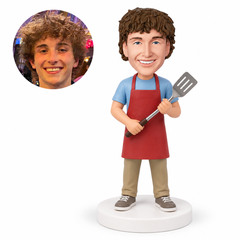 custom bobblehead figure man in an apron holding a spatula with both hands