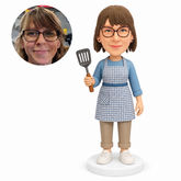 custom bobblehead figure woman in an apron holding a slotted spatula