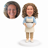 custom bobblehead figure woman in an apron holding a mixing bowl with a whisk