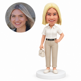 custom bobblehead figure woman in a short-sleeve collared shirt holding a handbag with one hand on her hip