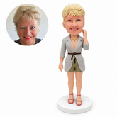 custom bobblehead figure woman in a belted long jacket and shorts with one hand beside her hair