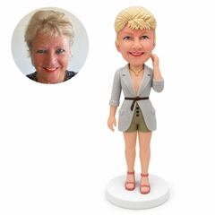 custom bobblehead figure woman in a belted long jacket and shorts with one hand beside her hair