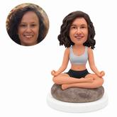 custom bobblehead figure woman meditating cross-legged on a rounded rock seat