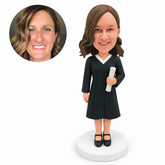 custom bobblehead figure female graduate in a knee-length gown holding a diploma with one hand