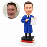 custom bobblehead figure male graduate standing on books and pointing to a certificate