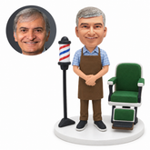 custom bobblehead figure barber in an apron with hands clasped beside a barber chair and pole