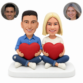custom bobblehead figures couple sitting cross legged each holding a heart
