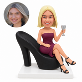 custom bobblehead figure woman sitting on a giant high heel shoe chair with a goblet