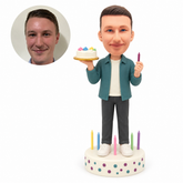 custom bobblehead figure man holding a birthday cake while standing on a cake base