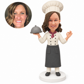 custom bobblehead figure female chef holding a cloche and making an OK gesture