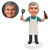 custom bobblehead figure man in an apron raising a spatula and a beer bottle