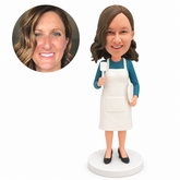 custom bobblehead figure woman in a long apron holding a spatula and a plate