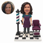 custom bobblehead figure female hairdresser in an apron holding a comb and clippers beside a salon chair and barber pole