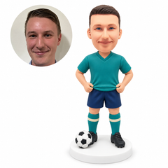 custom bobblehead figure male soccer player holding jersey hem with ball on base; original Bobblefigurine sculpted clay head and matching human portrait.