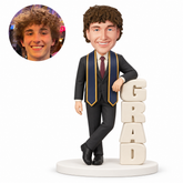 custom bobblehead figure male graduate leaning on vertical grad letters