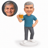 custom bobblehead figure man in a short-sleeve t-shirt and trousers raising a beer mug with one hand on his hip – original polymer-clay sculpture head and matching photo