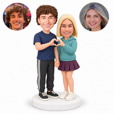 custom bobblehead figures couple with woman in a hoodie and short skirt making a shared heart while holding hands