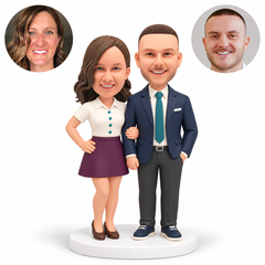 custom bobblehead figures couple linking arms with the woman resting one hand on her hip and the suited man keeping his other hand in his pocket