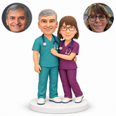 custom bobblehead figures doctor couple in scrubs embracing with the woman resting one hand across the mans chest