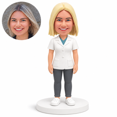 custom bobblehead figure female doctor in a short sleeve buttoned medical coat and trousers with both arms lowered with original clay head and matching photograph