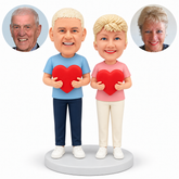 custom bobblehead figures older couple in t shirts and trousers each holding a separate heart