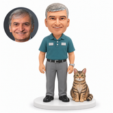 custom bobblehead figure man in a polo shirt standing beside a seated tabby cat