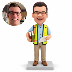 custom bobblehead figure male engineer cradling two closed books and holding a loose plan sheet