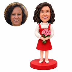 Custom bobblehead woman in a red pinafore over a white knit sweater holding pink roses, with matching portrait