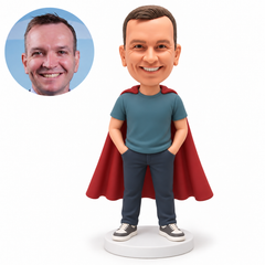 Custom polymer-clay bobblehead man in a teal T-shirt and burgundy cape with both hands in separate trouser pockets, with matching portrait photo