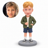 Custom polymer-clay boy in an olive jacket with his left hand inside the jacket patch pocket and right hand at the jacket front, with matching real child portrait