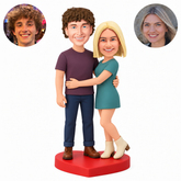 Custom polymer-clay couple with her hand low across his waist and his outer arm lowered, on a red heart base, MGA-AC1785