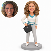 Custom polymer-clay woman with her right forearm bent to grip a tilted black handbag in front of her waist, left arm lowered, ivory and teal top, gray trousers and matching real photo circle.