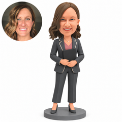 Custom polymer-clay businesswoman in a charcoal suit holding a closed black portfolio against her torso, with both hands overlapping along its lower front edge and a matching real photo circle.