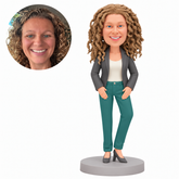 Clay woman in an open charcoal blazer, ivory top and teal trousers, both palms on front thighs and left knee relaxed, gray high heels and round base, with matching real portrait.