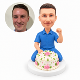 custom bobblehead figure man kneeling behind a decorated birthday cake