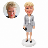 custom bobblehead figure woman in a skirt suit holding a small clutch bag at her side