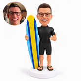 custom bobblehead figure male surfer in a short wetsuit holding a board and making a shaka sign
